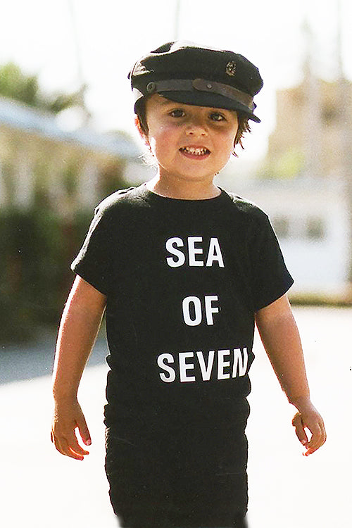 Toddler model River English wearing black tee Next Hero by Sea Of Seven with Fallen Broken Street hat and Zara pants with Vans shoes.