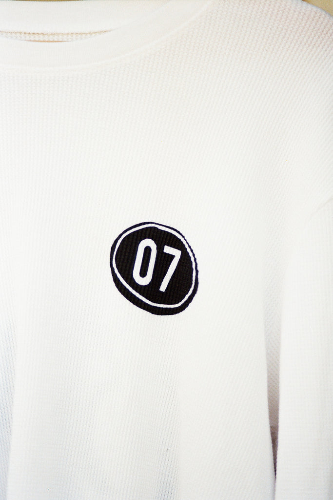 White sweatshirt with a black and white patch featuring the number '07'.