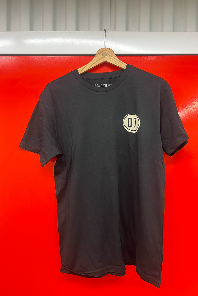 Black t-shirt with a logo on a hanger against a red background