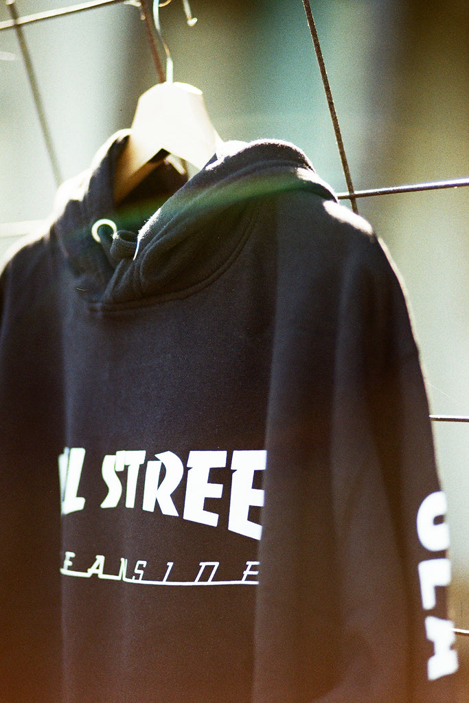 Black hoodie with white text on a hanger against a blurred background