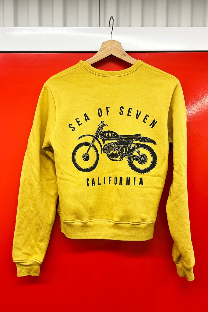 Yellow sweatshirt with motorcycle graphic and text reads sea of seven california on a red background.