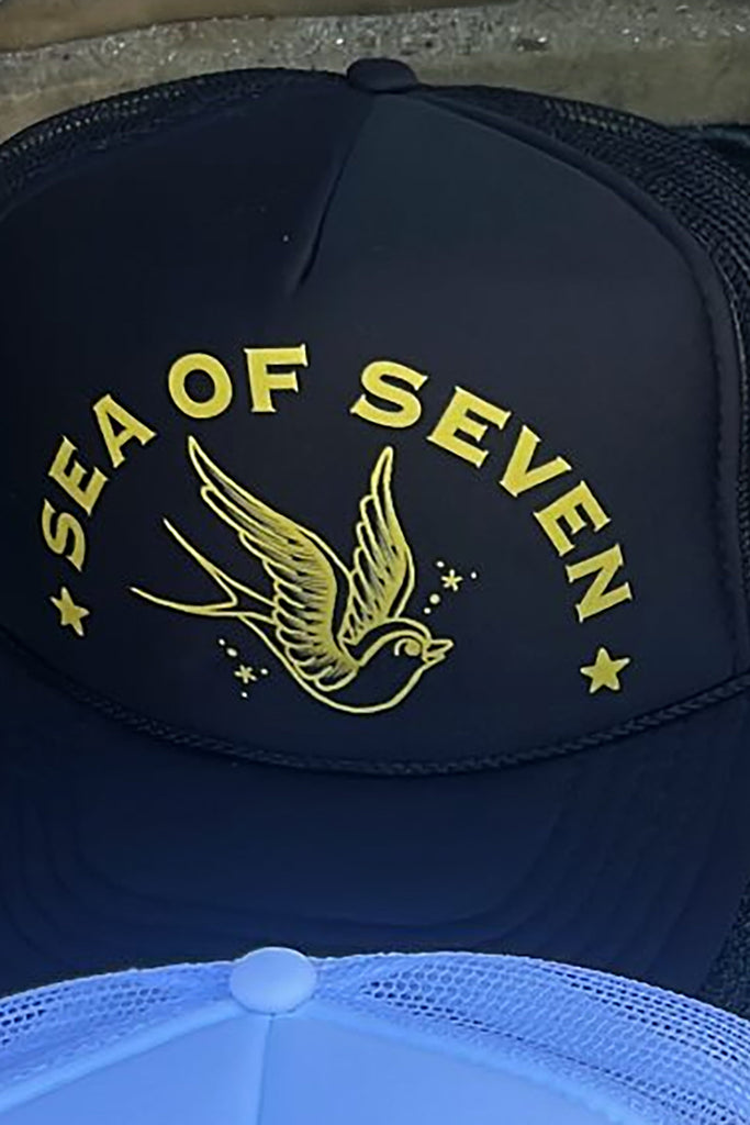 black cap with sea of seven and a swallow bird graphic