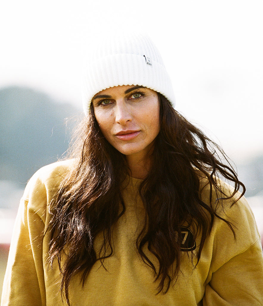 women wearing a white beanie and a mustard yellow sweatshirt.