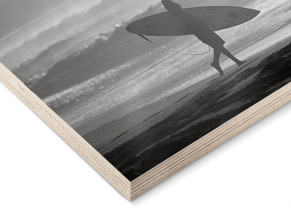 Surfer walking on beach holding surfboard black and white at Off The Wall on the North Shore of Oahu in Hawaii wood print